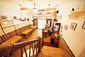 A restaurant interior with wooden tables and chairs, a counter, and a staircase. - Kulangsu Xinyuan Inn (Longtou Road Snack Street) (Xiamen)