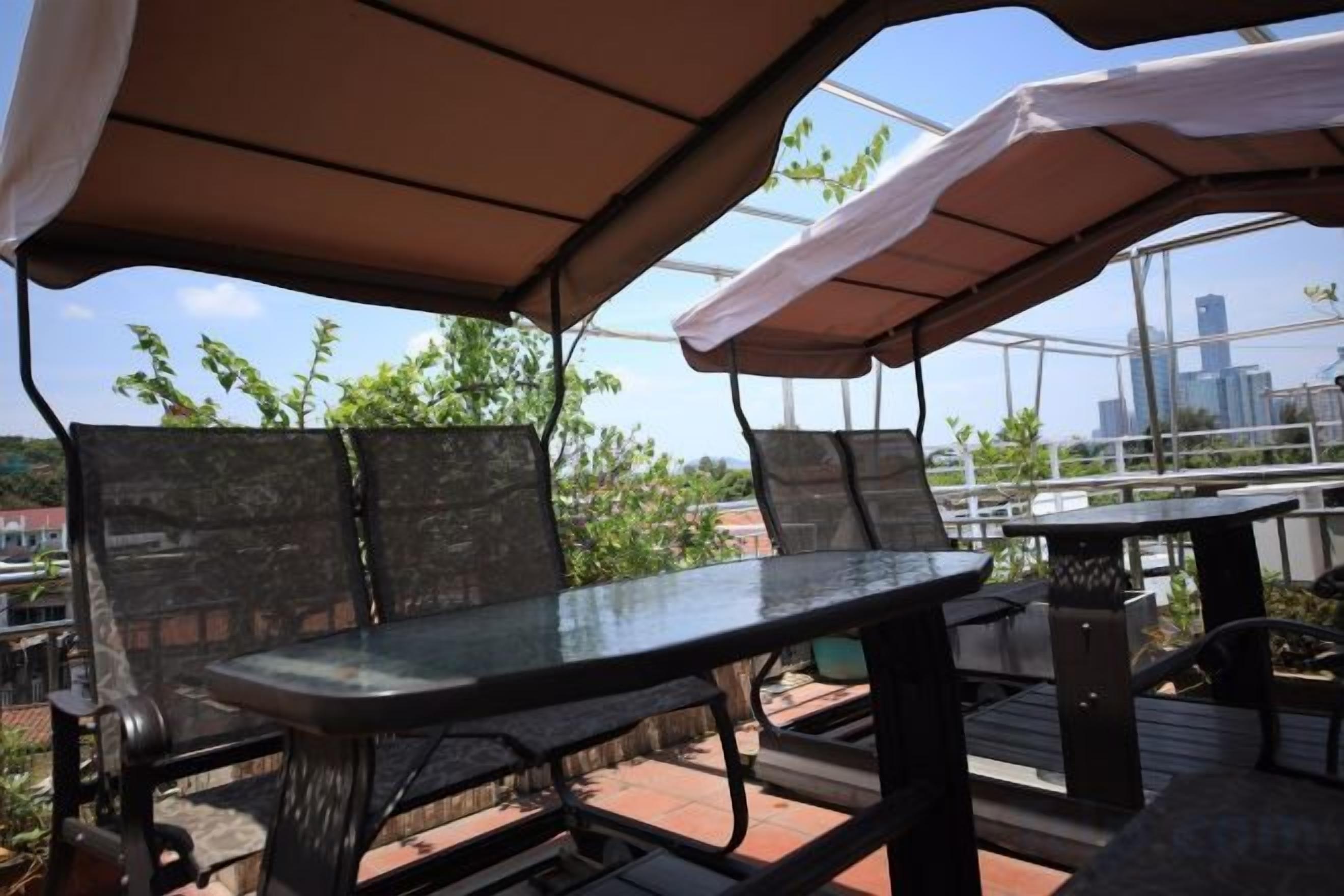 An outdoor patio with a table and chairs, a covered area, and a view of a cityscape.