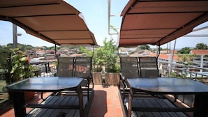 A terrace with two tables and chairs, covered by umbrellas, overlooking a cityscape. - Kulangsu Xinyuan Inn (Longtou Road Snack Street) (Xiamen)