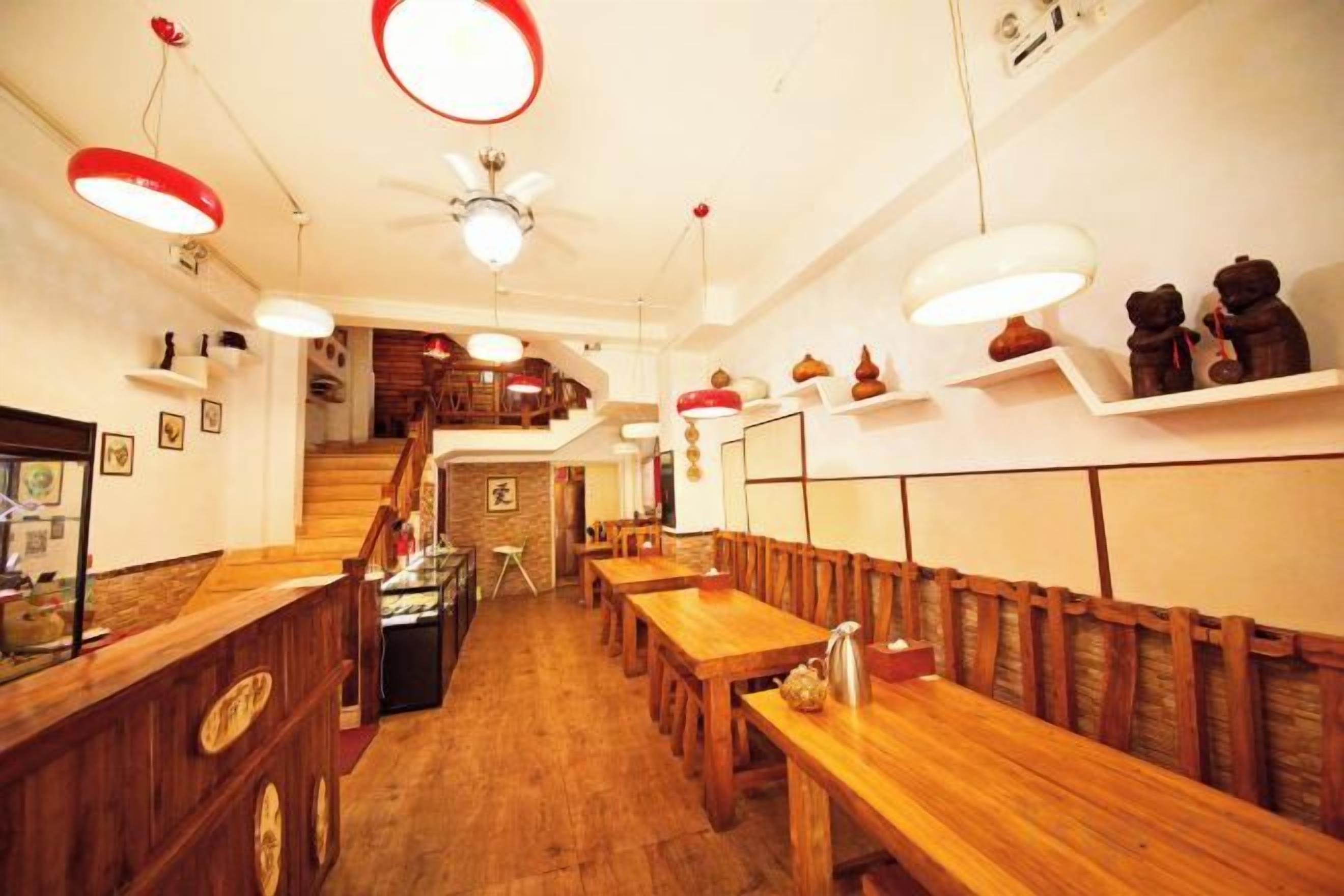 L’intérieur d’un restaurant avec des tables et des bancs en bois, un escalier et des luminaires suspendus.