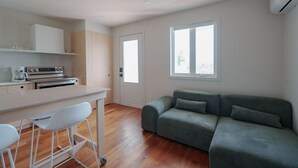 Een moderne keuken met witte kasten, een inbouwoven en een bar met krukken.