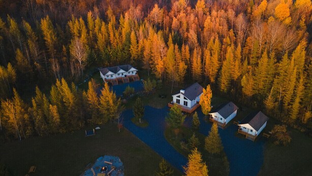 Luchtbeeld van een woongebied met drie huizen en een klein meer.