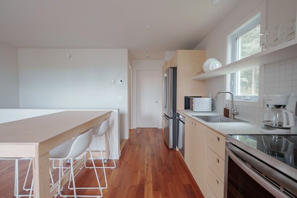 Una cocina moderna con una isla central, electrodomésticos de acero inoxidable y un ventanal que aporta luz natural.