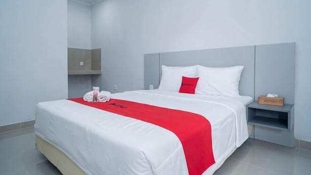 Una camera d'albergo con un letto, un comodino, una mensola e uno specchio.