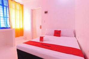 A hotel room with a bed, a red blanket, and a window with curtains. - RedDoorz @ Jolly Orange Paranaque (Parañaque)