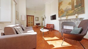 A spacious living room with a fireplace, a large painting, and a view into another room. - Spanish Steps apartment with view by Flatinrome (ROMA)