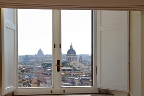 A view from a room with a large window, featuring a cityscape with prominent domed buildings. - Spanish Steps apartment with view by Flatinrome (ROMA)