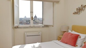 A hotel room with a bed, a window with a view of a cityscape, a bedside table with a lamp, and a radiator. - Spanish Steps apartment with view by Flatinrome (ROMA)