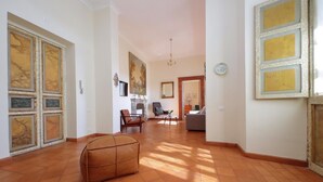 A spacious living area with a tiled floor, a brown leather ottoman, a fireplace, and a dining area with a table and chairs. - Spanish Steps apartment with view by Flatinrome (ROMA)