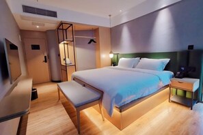 A modern hotel room with a bed, bedside table, bench, and a wardrobe with a mirror. - Puyue Hotel (Shenzhen East Railway Station Buji Metro Station) (Shenzhen)