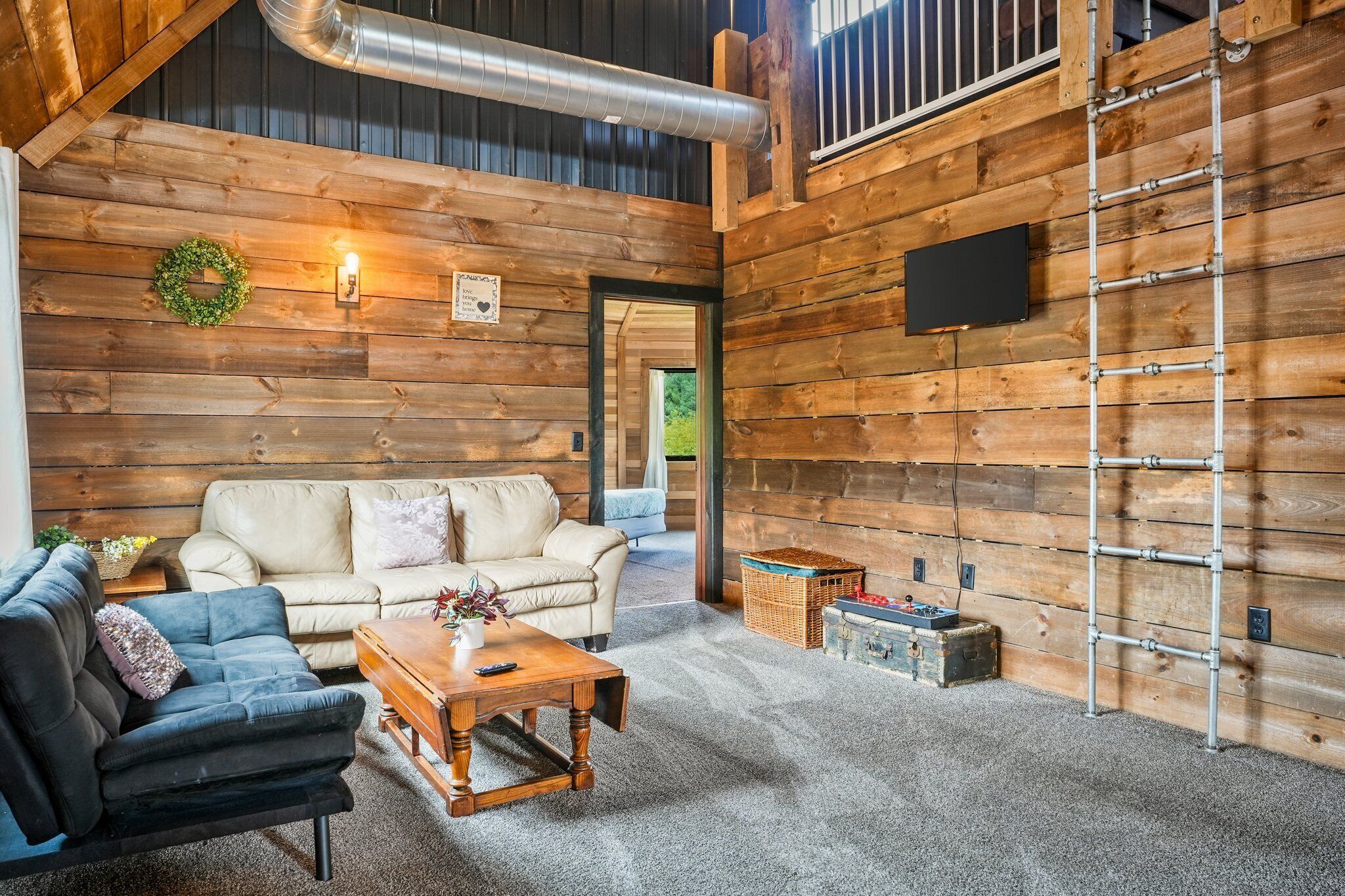 A cozy log cabin interior with a sofa, a coffee table, and a ladder against the wall.