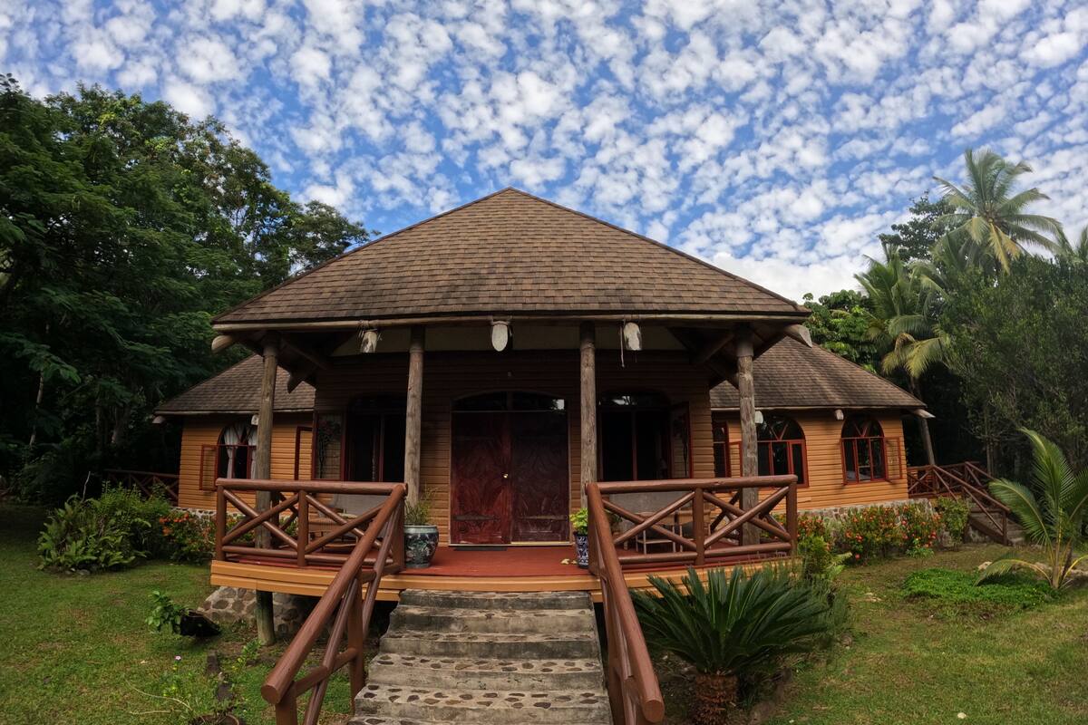 Eine Holzhütte mit Veranda, Steintreppe und rotem Teppich.