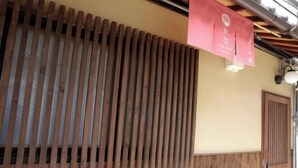 A traditional Japanese building with wooden slats and a red hanging sign. - Kyokoi Toujimikuni (Kyoto)
