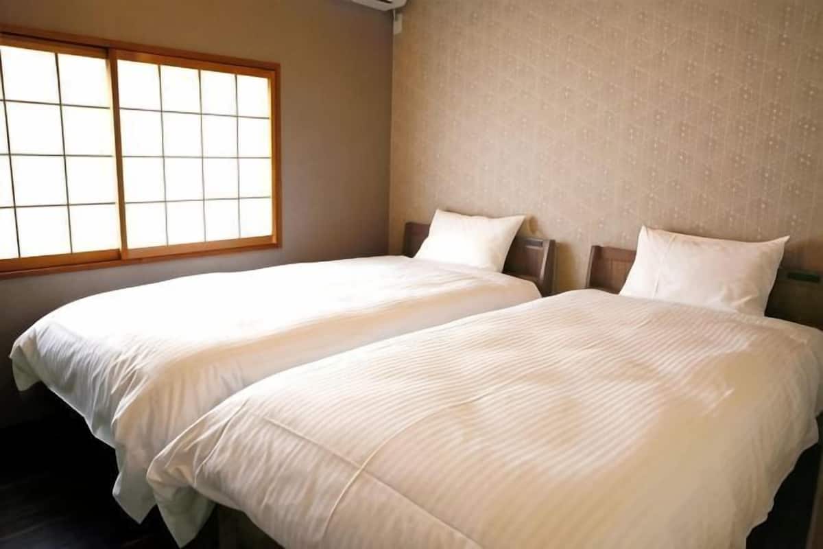 Una habitación con dos camas, un ventanal grande y una pared con textura.