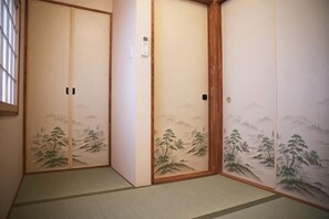 A traditional Japanese room with tatami flooring, sliding doors with mountain landscape paintings, and a wooden door frame. - Kyokoi Toujimikuni (Kyoto)