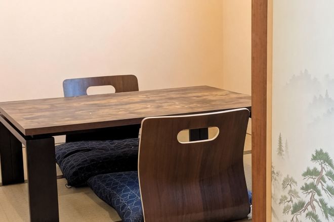 A wooden dining table with chairs, a bench, and a wall with a nature-themed mural.