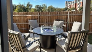 A patio with a round table and four chairs, a glass-top table, and a wooden fence in the background. - 5BR/5BA Arlington Getaway w/ Private Hot Tub Close to UTA & AT&T (Arlington)