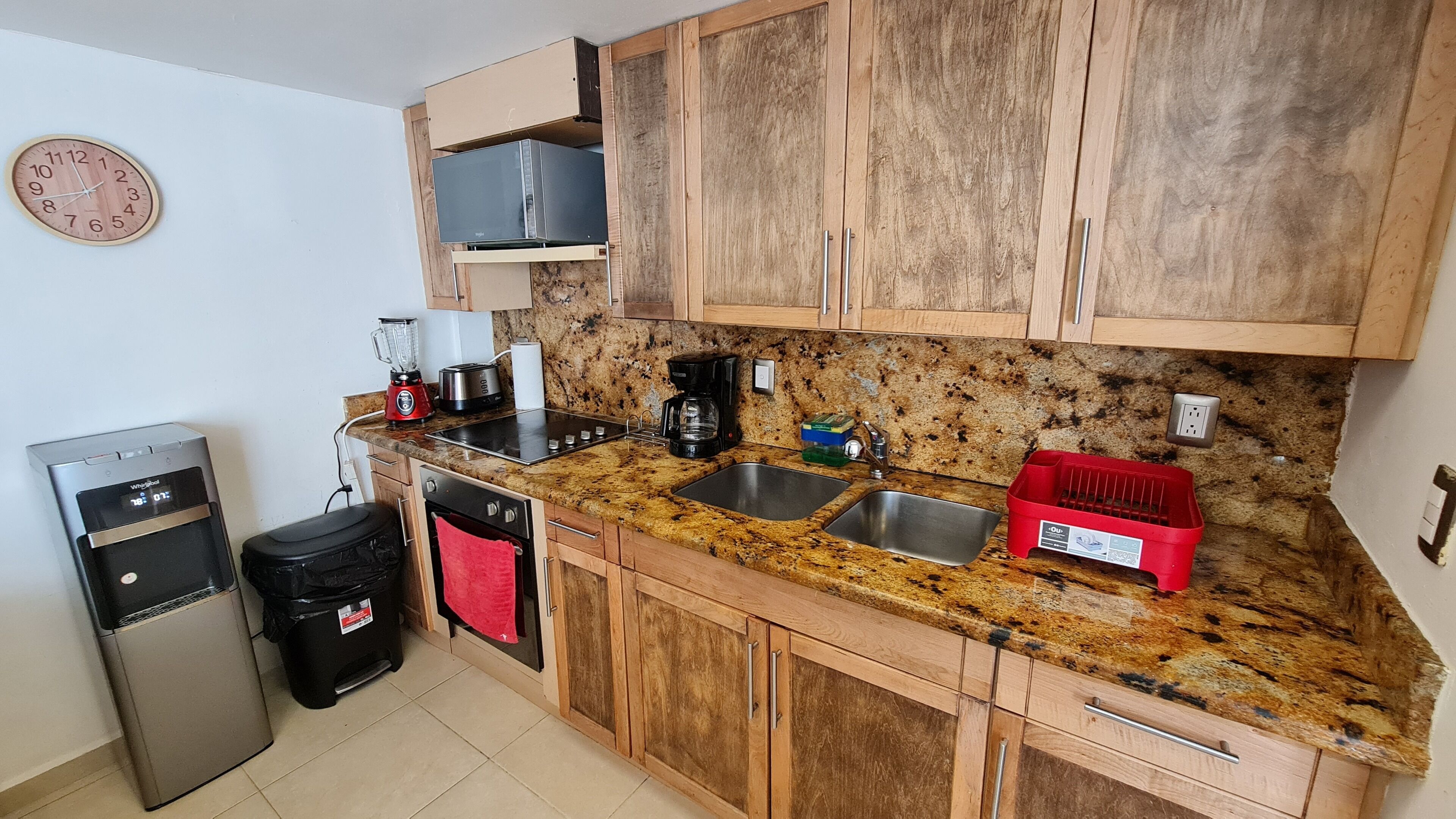 A kitchen with wooden cabinets, granite countertops, a stainless steel sink, a coffee maker, a toaster, and a dishwasher.