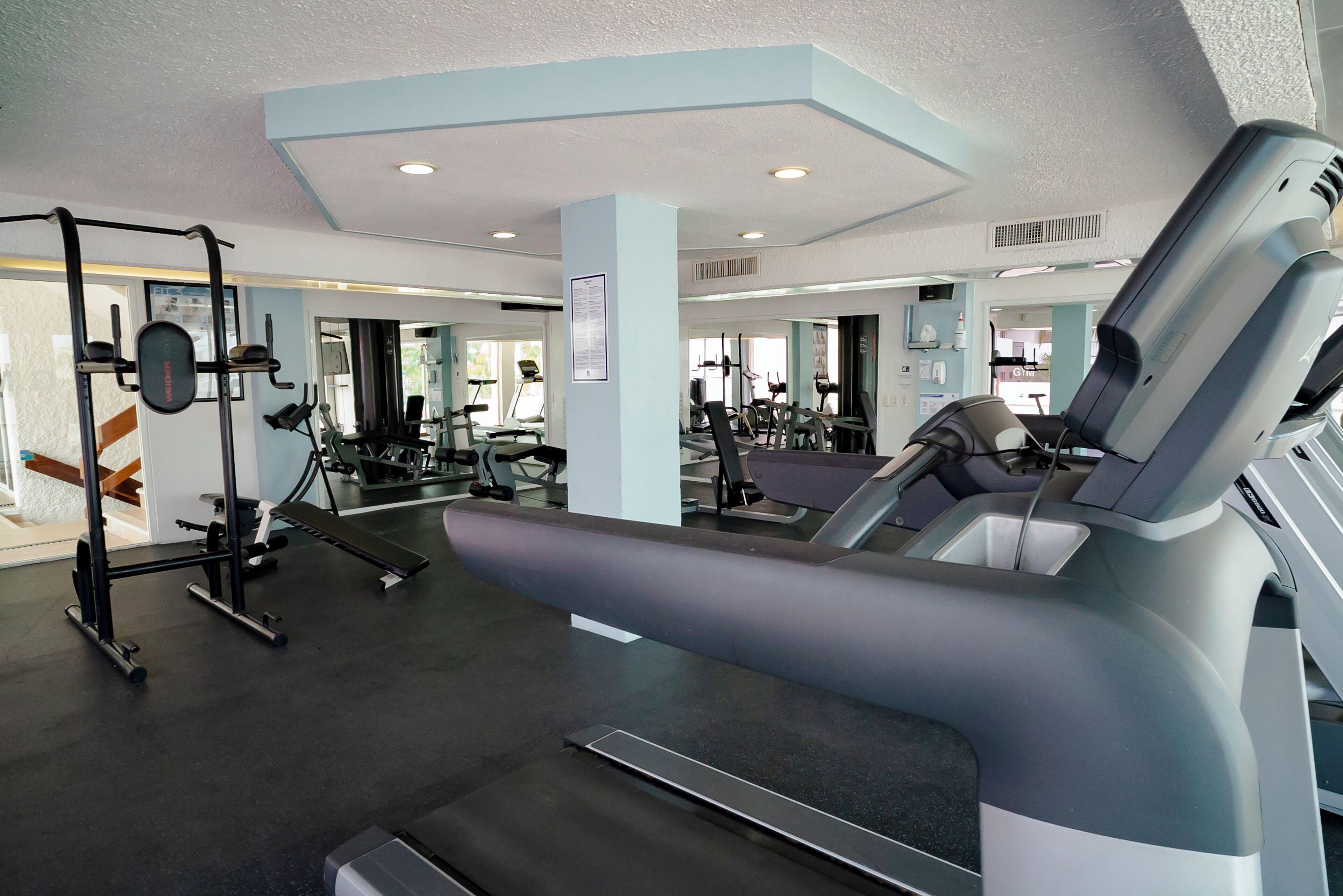 Uma academia com equipamentos de ginástica, esteira e banco de musculação.