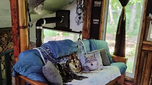 Una cama de madera rústica con colcha azul y blanca, rodeada de almohadas y una manta.
