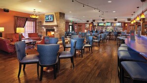 A bar area with multiple seating options, including bar stools and chairs, and a fireplace.