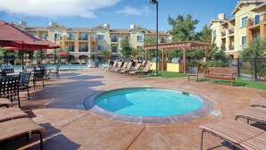 A pool area with lounge chairs and umbrellas, surrounded by multi-story buildings with balconies. - Napa Valley | Napa Wine Getaway | Pool & Hot Tub (Napa)