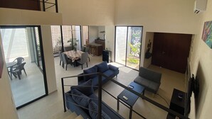 A spacious living area with a dining table, sofas, and a kitchen in the background. - VILLA GRACE tu mejor opcion en Cholul (Mérida)