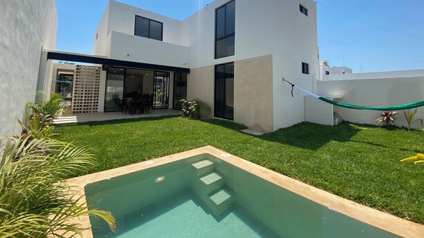A modern two-story house with a swimming pool, a patio with outdoor furniture, and a clear blue sky. - VILLA GRACE tu mejor opcion en Cholul (Mérida)