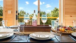 A wooden dining table set with plates, cutlery, glasses, and a charcuterie board. - Secluded Cabin with Hot Tub, Views, & EV Charger (Bryant Pond)