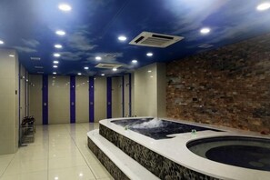 A spa room with a hot tub, tiled flooring, and a brick wall. - Pengcheng Holiday Hotel (Huma)