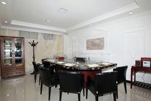A dining area with a round table, black chairs, and a glass cabinet.