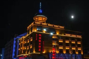 Un edificio de varios pisos con señalización iluminada y una destacada estructura de torre.