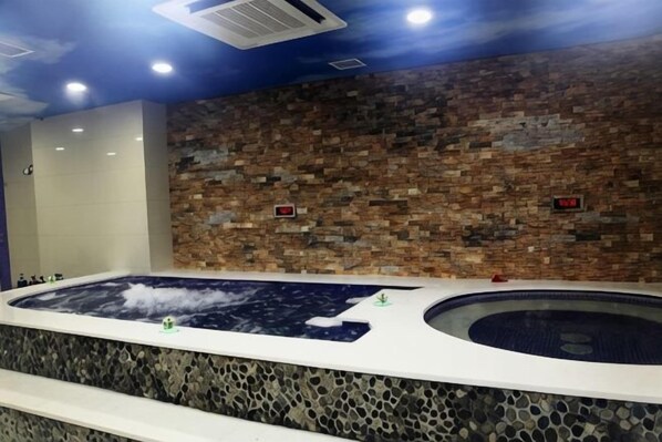 Un espace bien-être comprenant un jacuzzi et un mur en pierre.
