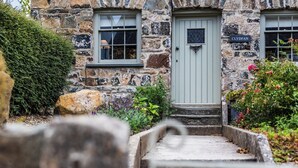 A stone building with a light blue door, a nameplate reading "Clydfan," and a small window with a grid pattern. - A character cottage with a contemporary glass extension, in the heart of Newport (Newport)