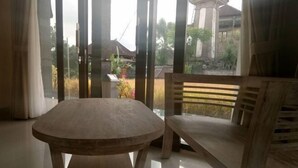 A wooden table and bench in a room with large windows. - Adi Bisma Inn by Mahaputra (Bali)