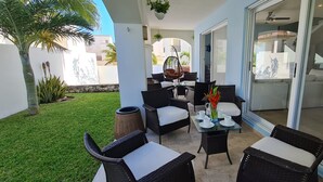 An outdoor patio with wicker furniture, a glass table, and a view of the interior. - CASA REYES Stunning Rooftop Oceanview (Isla Mujeres)