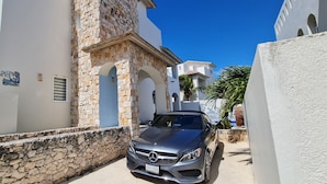 A narrow street with a stone wall and a parked Mercedes-Benz. - CASA REYES Stunning Rooftop Oceanview (Isla Mujeres)