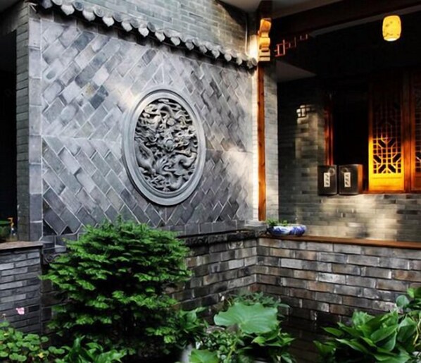 A building with a stone wall featuring a decorative dragon relief and a traditional Chinese window with intricate lattice design. - Shaoxing Dayue Xiaoyuan Culture Theme Hotel (Lu Xun's hometown Shenyuan Branch) (Shaoxing)