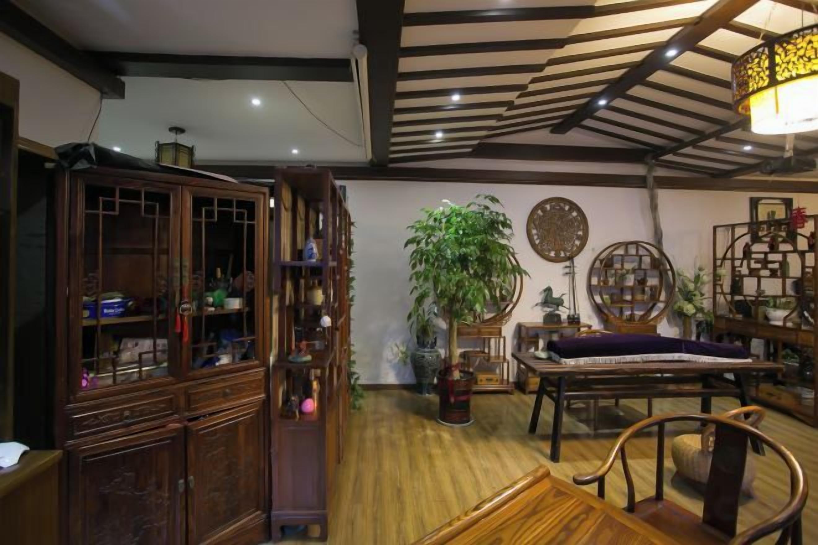 A traditional room with a wooden cabinet, a dining table, and a large potted plant.
