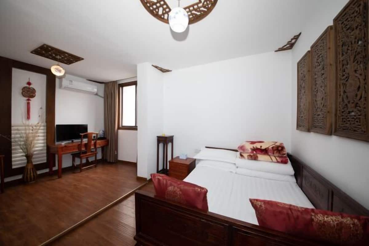Ein Schlafzimmer mit Bett, Schreibtisch, Sessel und Fernseher.