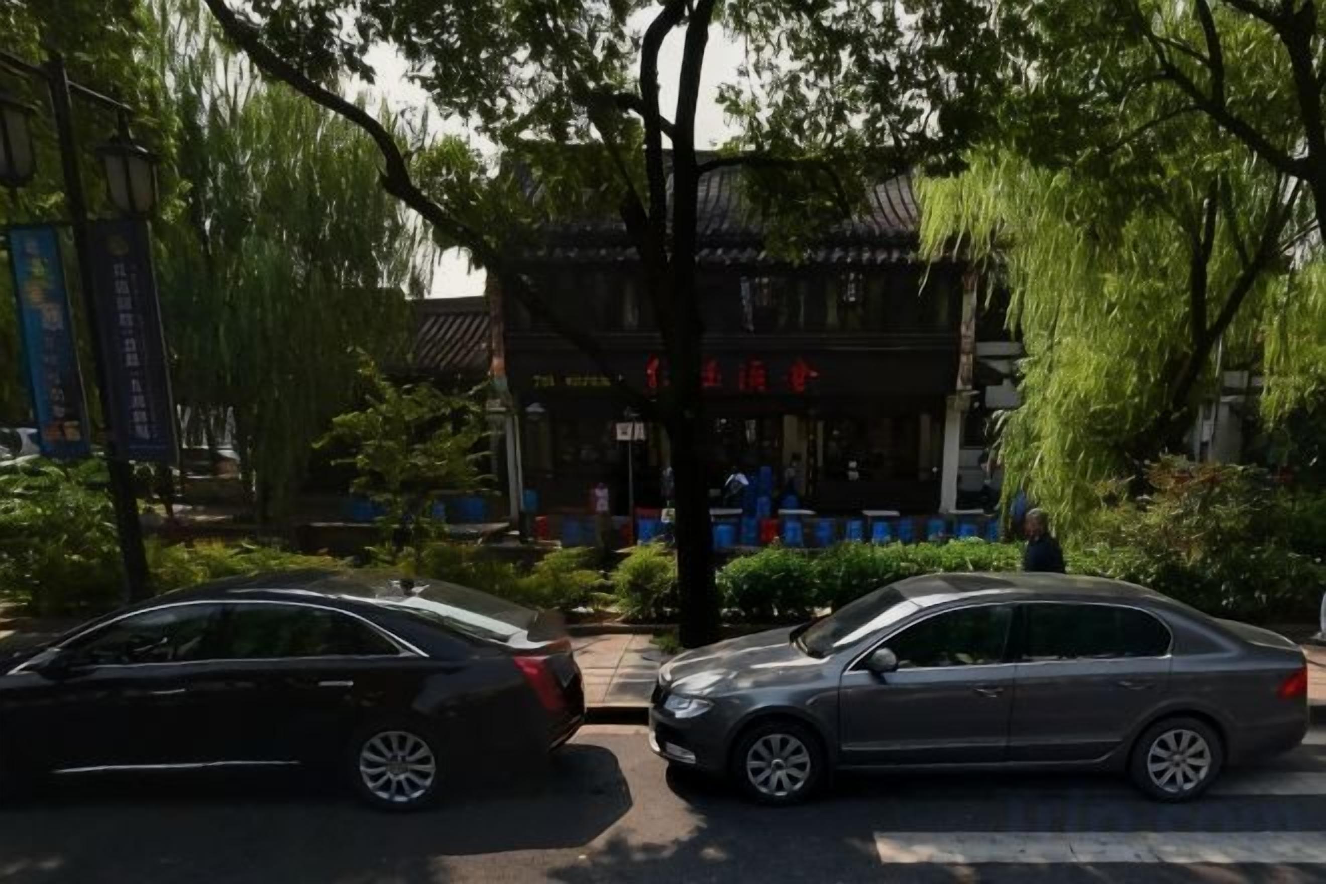 Dos coches estacionados frente a un edificio tradicional con un letrero en un idioma extranjero.