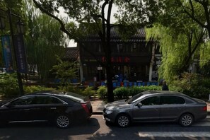 Two cars parked in front of a traditional building with a sign in a foreign language. - Shaoxing Dayue Xiaoyuan Culture Theme Hotel (Lu Xun's hometown Shenyuan Branch) (Shaoxing)