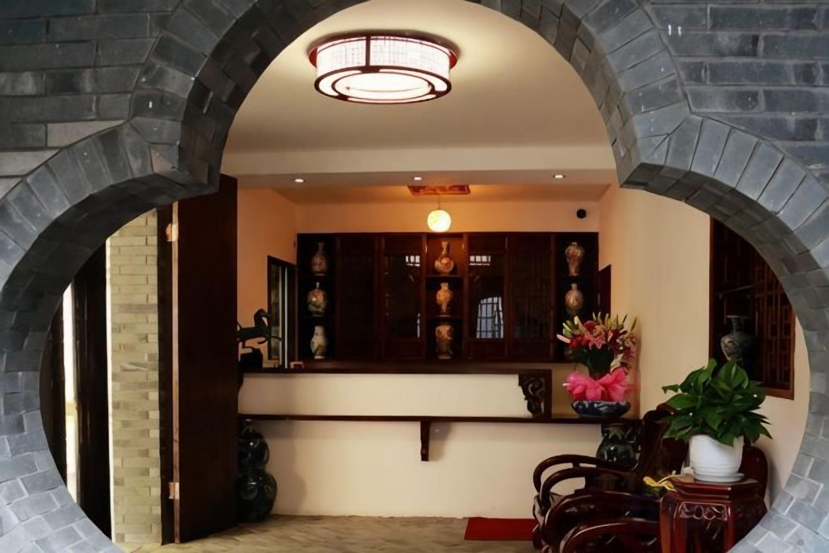 Un intérieur traditionnel avec une arche en pierre, une vitrine contenant des objets décoratifs et une plante en pot.