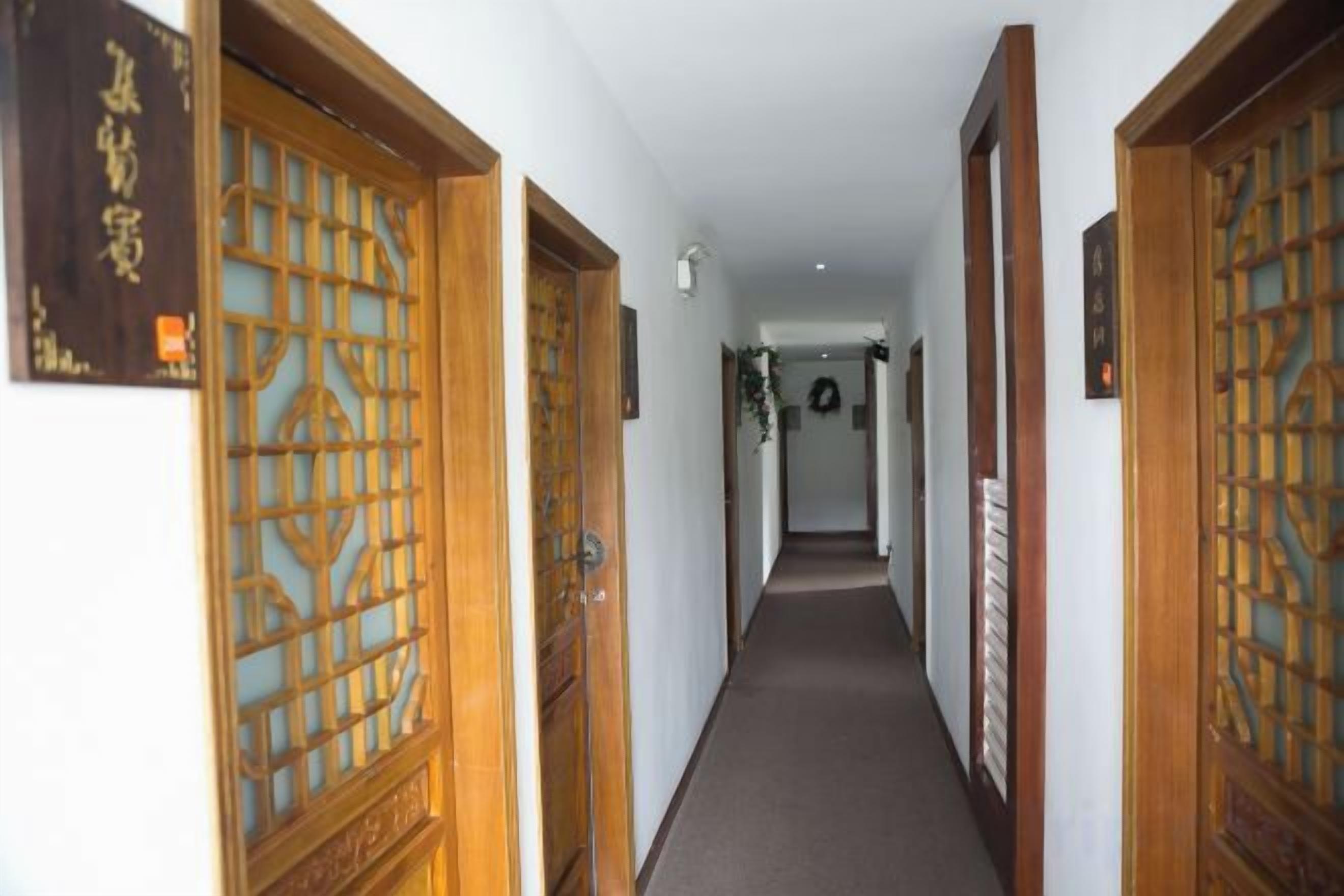 A corridor with traditional wooden doors and a carpeted floor.
