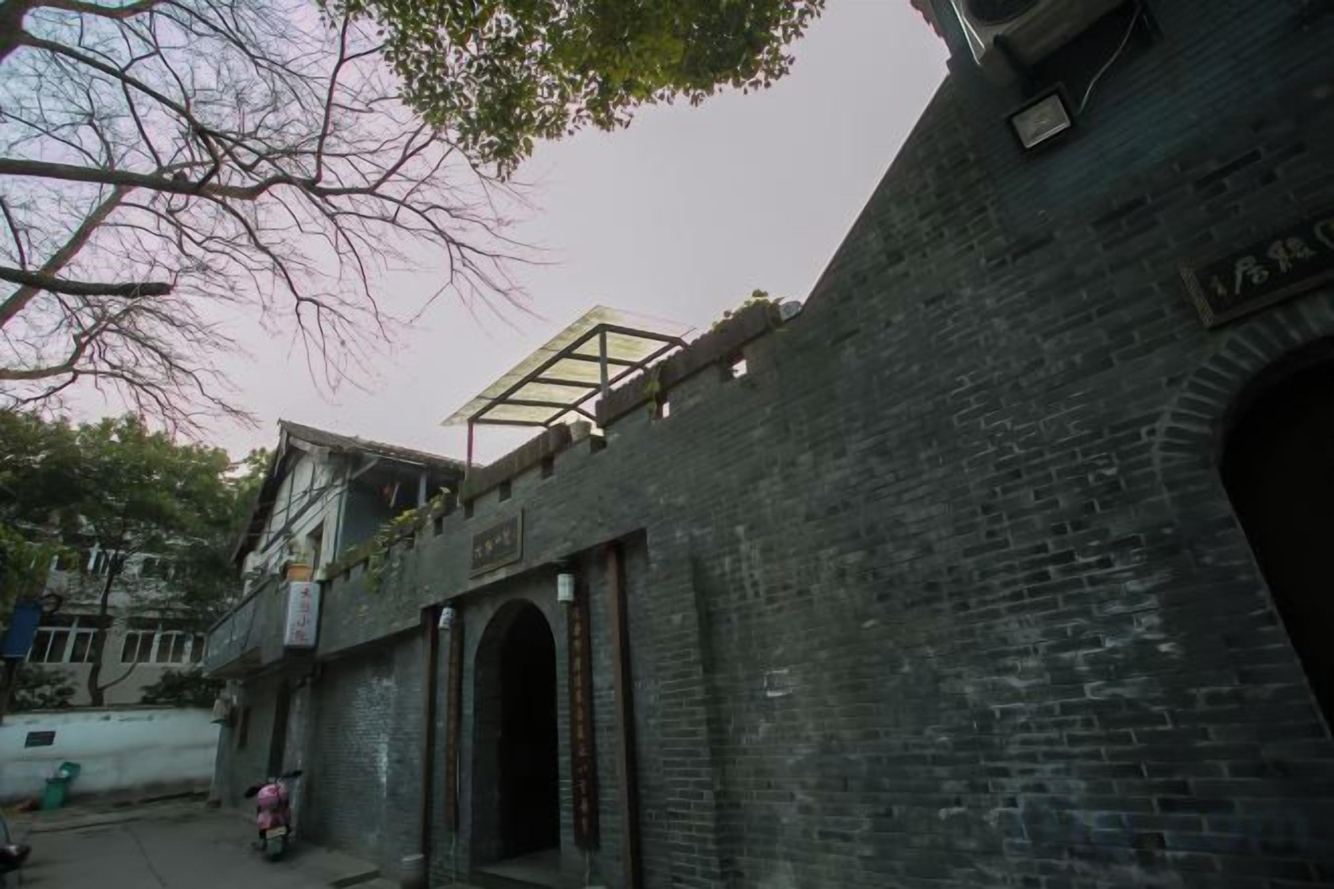 Edifício de tijolos com entrada em arco e um terraço coberto.