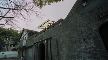 Edifício de tijolos com entrada em arco e um terraço coberto.