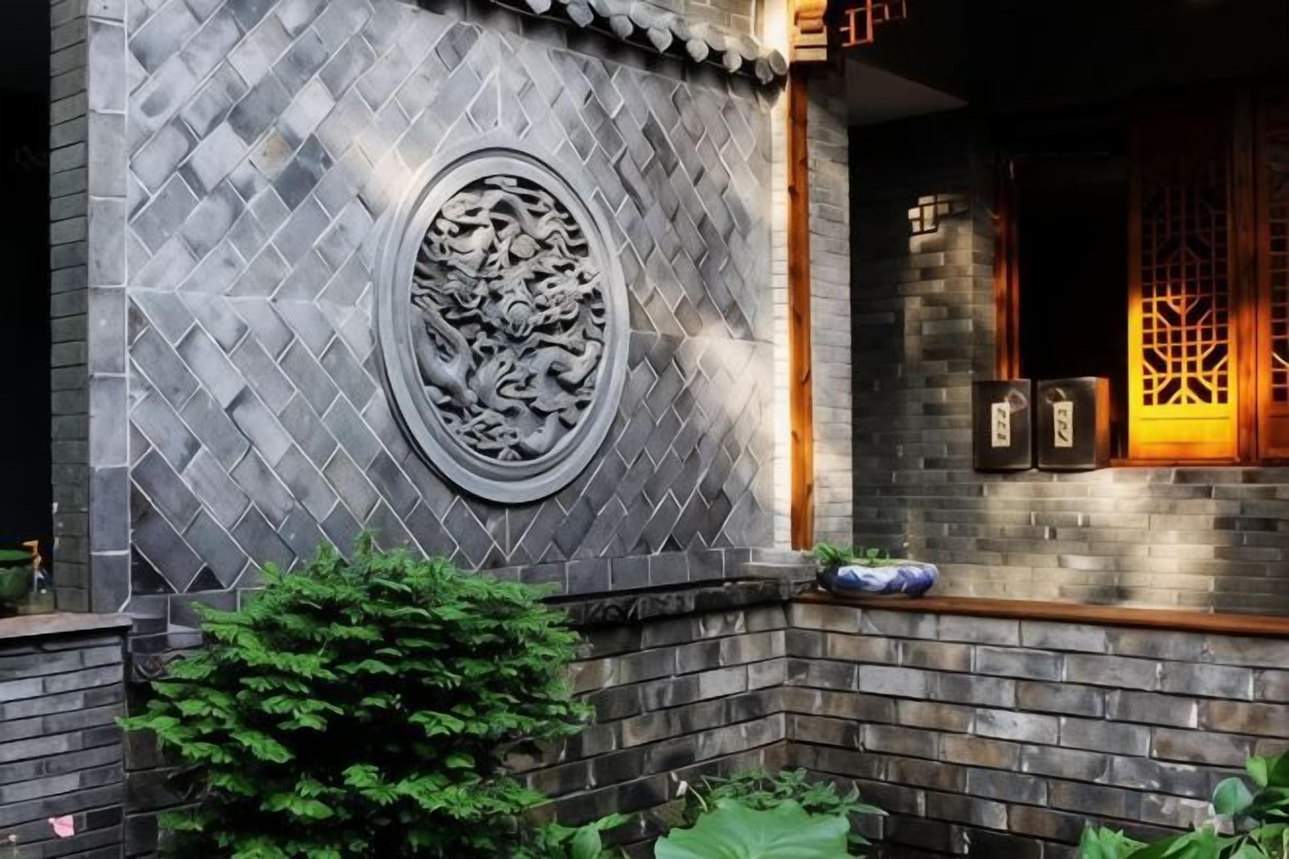 A traditional building with a tiled wall, a carved circular design, and a wooden door with a lattice pattern.