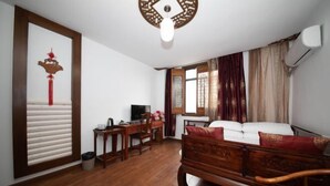 A room with a wooden bed, a desk with a chair, a television, and a decorative wall piece. - Shaoxing Dayue Xiaoyuan Culture Theme Hotel (Lu Xun's hometown Shenyuan Branch) (Shaoxing)