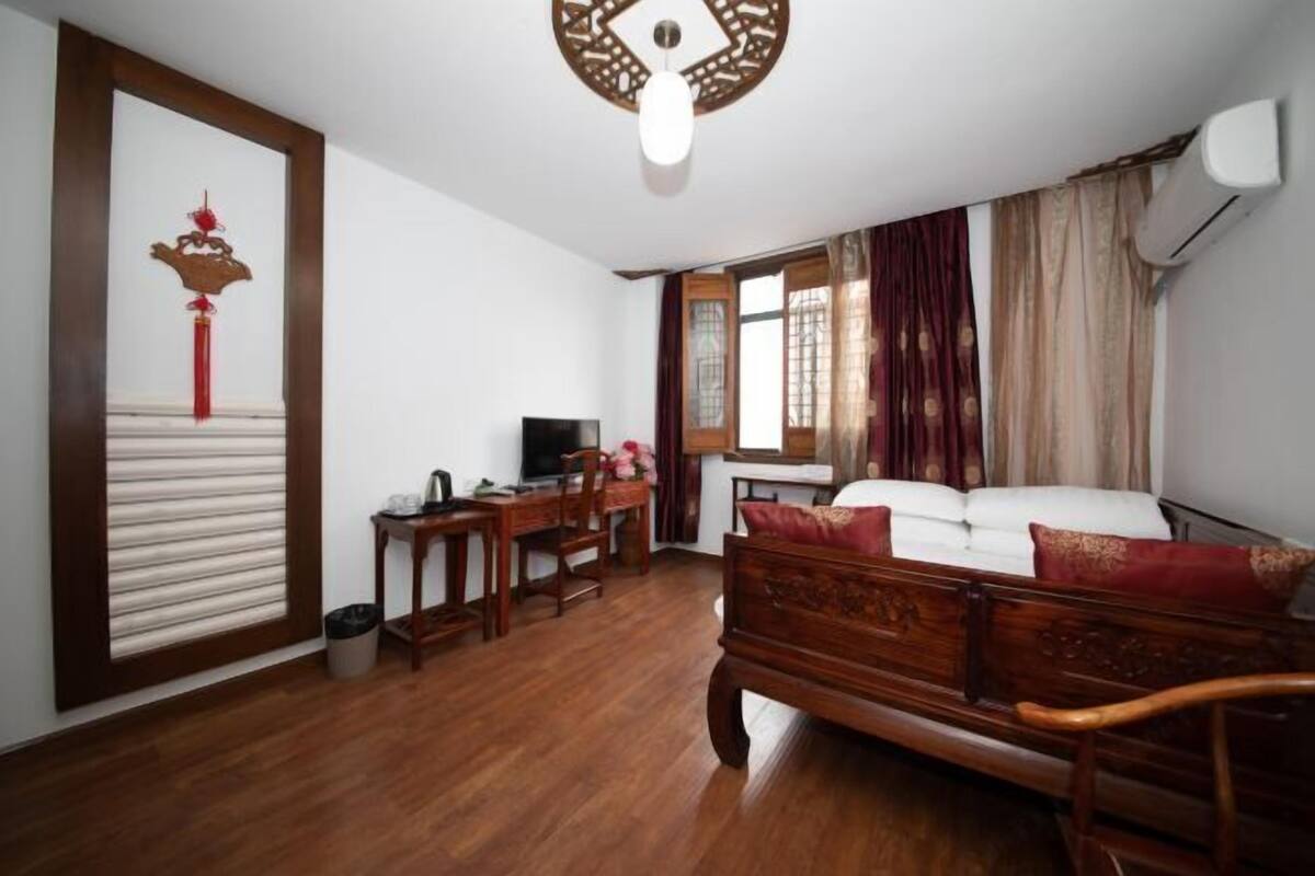 Ein Zimmer mit einem Holzbett, einem Schreibtisch mit Stuhl, einem Fernseher und einem Wanddekor.