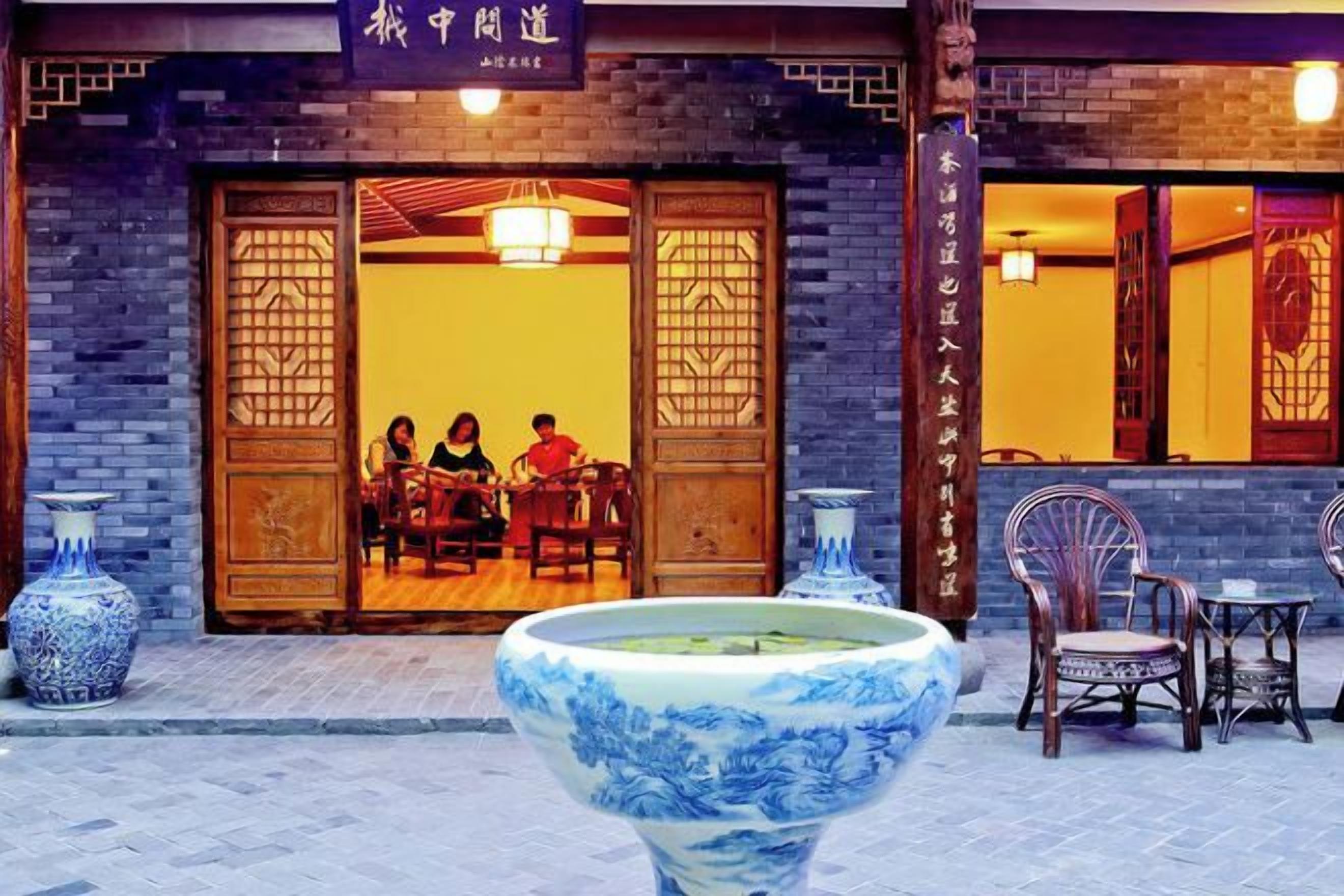 Un restaurante chino tradicional con puertas de madera y un gran jarrón azul de cerámica en primer plano.